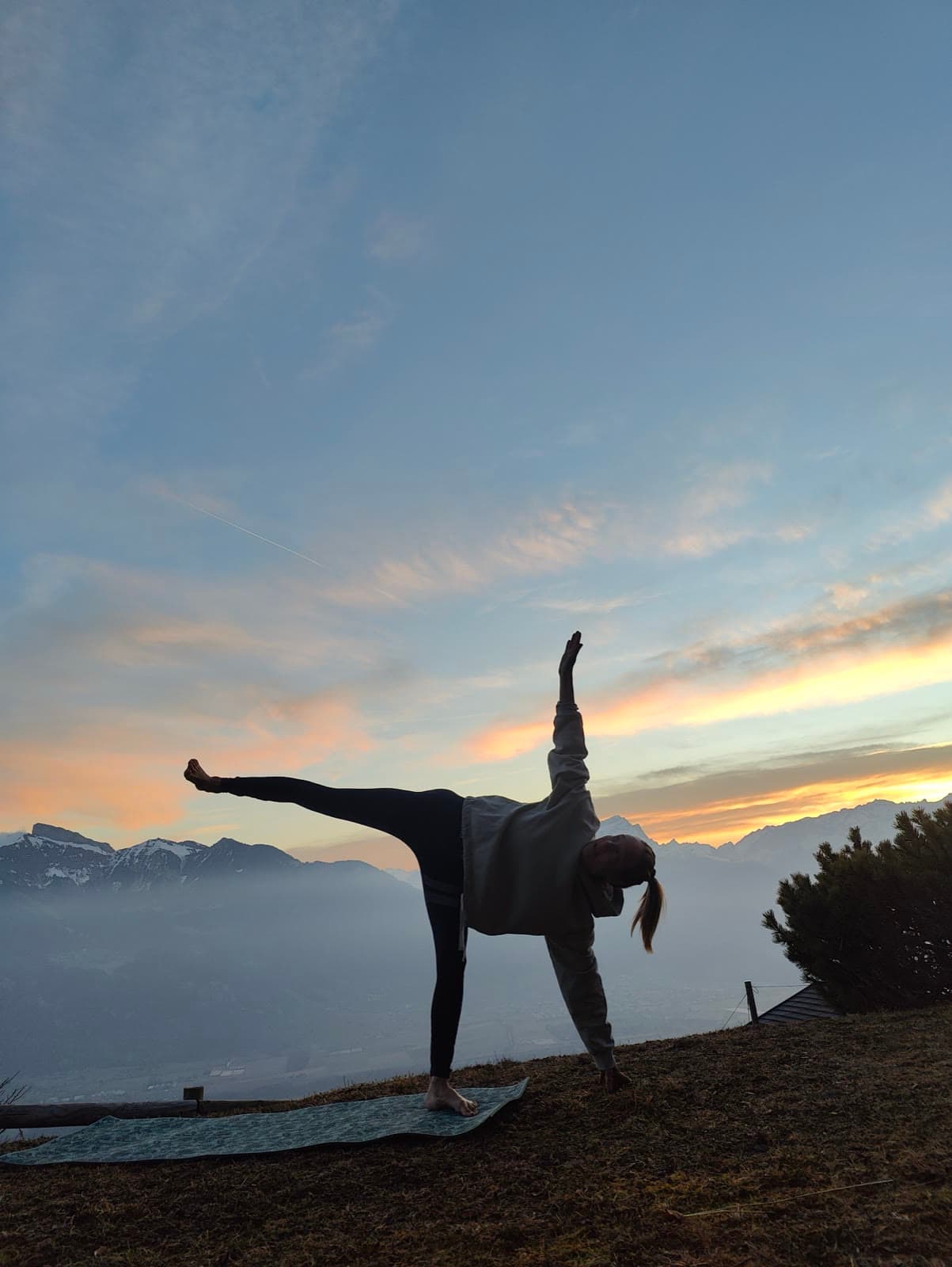 Léa en posture de la demi-lune, un bras vers le ciel, au lever du soleil en montagne