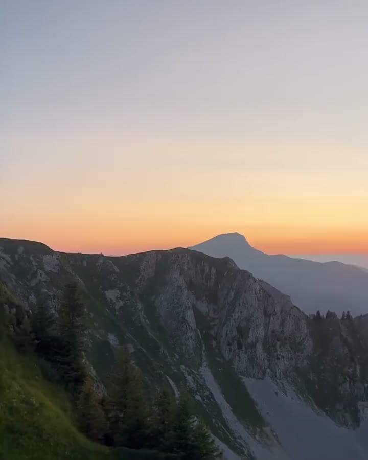 Le soleil bas sur l'horizon derrière une ligne de crêtes, puis les sommets et la vallée dans la brume